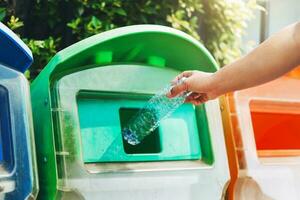 pessoas mão segurando lixo garrafa plástico colocando para dentro reciclar bin para limpeza foto