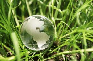 vidro globo na grama com sol. conceito de ambiente foto