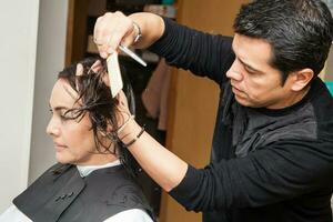 masculino estilista fazer uma corte de cabelo para uma branco mulher foto