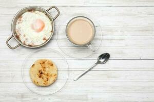 frito ovo, café e arepa em de madeira branco mesa foto