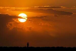 silhueta do uma homem e dele bicicleta às uma lindo pôr do sol Próximo para a mar foto