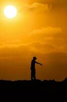 silhueta do dois homens às uma lindo laranja pôr do sol. ponting às alguma coisa às pôr do sol foto