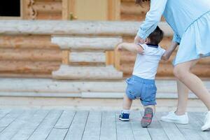 a Garoto aprende para andar e leva dele primeiro passos com dele mãe. bebê e dele primeiro passos. mãe Apoio, suporte para a criança foto