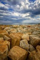 lindo pedra costa marinha com colorida pedras. vertical Visão foto