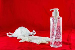 luvas de látex brancas de gel higienizante e máscara no conceito de proteção vermelha contra o vírus da poluição da gripe e do coronavírus foto
