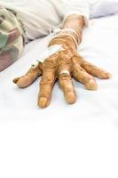 mão do paciente idoso com tampão na cama no hospital e área em branco na parte inferior foto