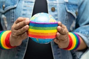 senhora asiática segurando a bandeira da cor do arco-íris com o símbolo do globo do mês do orgulho LGBT comemora anualmente em junho social de gays lésbicas bissexuais transgêneros direitos humanos foto