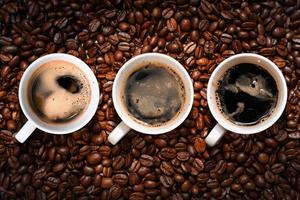 vista superior de três xícaras de café em uma pilha de grãos de café foto