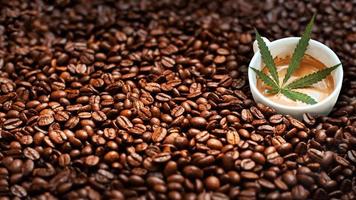 folha de cannabis em uma xícara de café em uma pilha de grãos de café