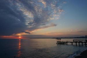 pôr do sol dramático com nuvens escuras sobre o mar calmo foto