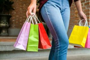 ásia meninas segurando venda compras bolsas. consumismo estilo de vida conceito dentro a compras shopping center. senhora turista andar compras Centro com compras bolsas foto