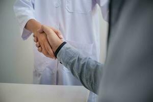 médico assistência médica. profissional médico médico dentro branco uniforme vestido casaco entrevista consultando paciente tranquilizador dele masculino paciente ajudando mão foto
