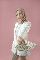 jovem muçulmano mulher aguarde dinheiro em isolado fundo. foto