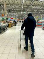 homem com compras carrinho dentro supermercado foto