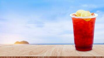 gelado chá e limão fatias em de madeira mesa com de praia panorama natureza fundo, verão bebidas com gelo foto