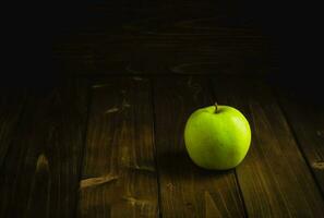maduro verde maçã em uma de madeira mesa em uma Sombrio fundo foto