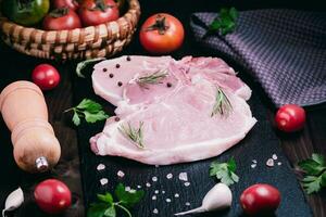 cru carne de porco eu no. fresco bifes em ardósia borda em Preto fundo. lado visualizar. foto