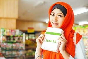 muçulmano mulher comprando halal Comida dentro uma supermercado foto