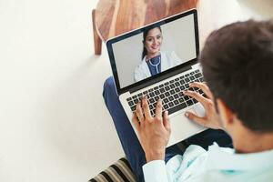 homem usando dele computador portátil para pegue médico consulta conectados a partir de indiano médico foto