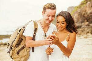 mestiço casal Viajantes olhando às a aplicativo em Móvel telefone foto