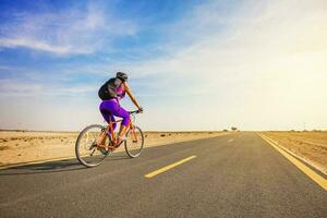 sem carro dia. mulher equitação bicicleta em uma estrada dentro deserto foto