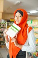 muçulmano mulher comprando halal Comida dentro uma supermercado foto