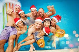 misturado correu grupo do nove pessoas a comemorar Natal dentro uma natação piscina foto