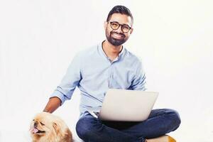 jovem indiano homem com pequinês cachorro usando computador para a veterinario consulta sobre branco fundo foto