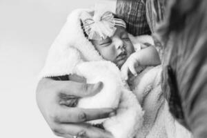 pequeno recém-nascido indiano menina dormindo dentro a mãos do dela pai foto
