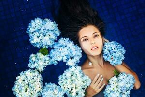 dramático retrato do uma mulher flutuando a uma natação piscina cheio do flores foto