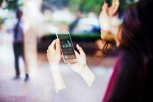 a indiano mulher segurando uma Móvel telefone com gráficos foto