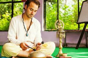 misturado raça homem jogando mantras em uma aguentar tambor foto