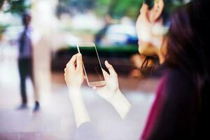 a indiano mulher segurando uma Móvel telefone com uma em branco tela dentro dela mãos tiro a partir de atrás foto