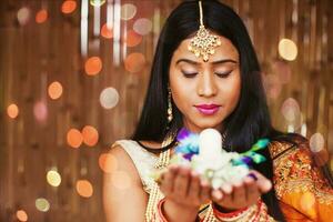 lindo indiano mulher segurando tremor dentro dela mãos em Shivratri noite e Rezar para Deus, meditando foto