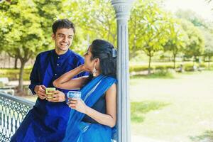 lindo indiano casal vestindo tradicional roupas bebendo café ou chá em uma sacada e falando foto