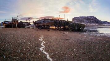 a velho oxidado pescaria barco abandonado de uma tempestade em a costa. cemitério do navios, velho pescaria Vila em a costa do a barents mar, a cola Península, teriberka foto