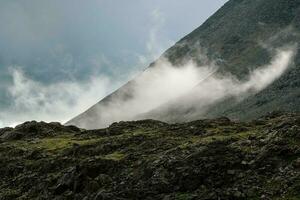 baixo nuvens, mutável clima dentro a montanhas. cênico alpino panorama com cinzento baixo nuvens e luz solar. foto