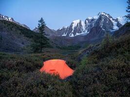 fofo laranja barraca às crepúsculo dentro a montanhas. acolhedor acampamento dentro a legal outono montanhas. foto