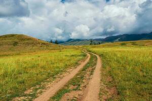 caminho para a distância, caminho sobre a Colina para a céu. sujeira estrada através a campo. atmosférico nebuloso montanha cenário com comprimento estrada entre colinas. foto