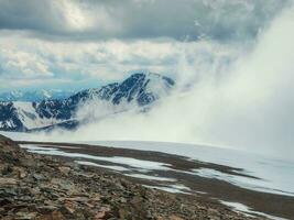 tempestade em a topo do uma montanha. Maravilhoso dramático panorama com grande Nevado montanha picos acima baixo nuvens. atmosférico ampla neve montanha tops dentro nublado céu. foto