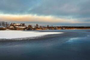 inverno Visão com velho casas perto uma coberto de neve lago. autêntico norte cidade do kem dentro inverno foto