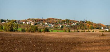 uma Largo panorama do a coletivo Fazenda campo dentro frente do a Vila em uma verde colina. foto