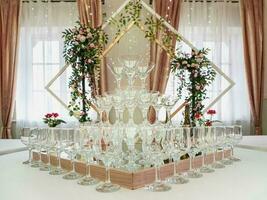 esvaziar vinho óculos em uma mesa estão uma pirâmide. lindo Casamento cerimônia dentro de casa. foto