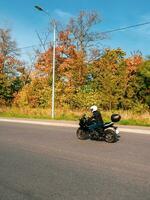motociclista dentro movimento. motociclista em uma Preto motocicleta dentro tráfego em uma rural outono estrada foto