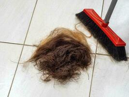 uma pilha do cortar cabelo em a barbeiro fazer compras chão Próximo para uma vassoura foto