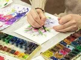 escova dentro a mãos do a artista, aguarela pintura, criatividade com muitos cores. foto