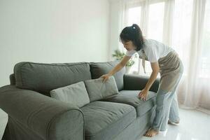 mulher limpeza e arranjo sofá almofadas às lar. foto