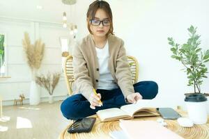 jovem colagem aluna lendo uma livro sentado dentro uma cadeira. foto