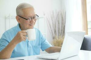 Senior homem usando computador portátil às lar. foto