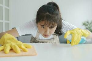 jovem mulher limpeza mesa vestindo luvas às lar. foto
